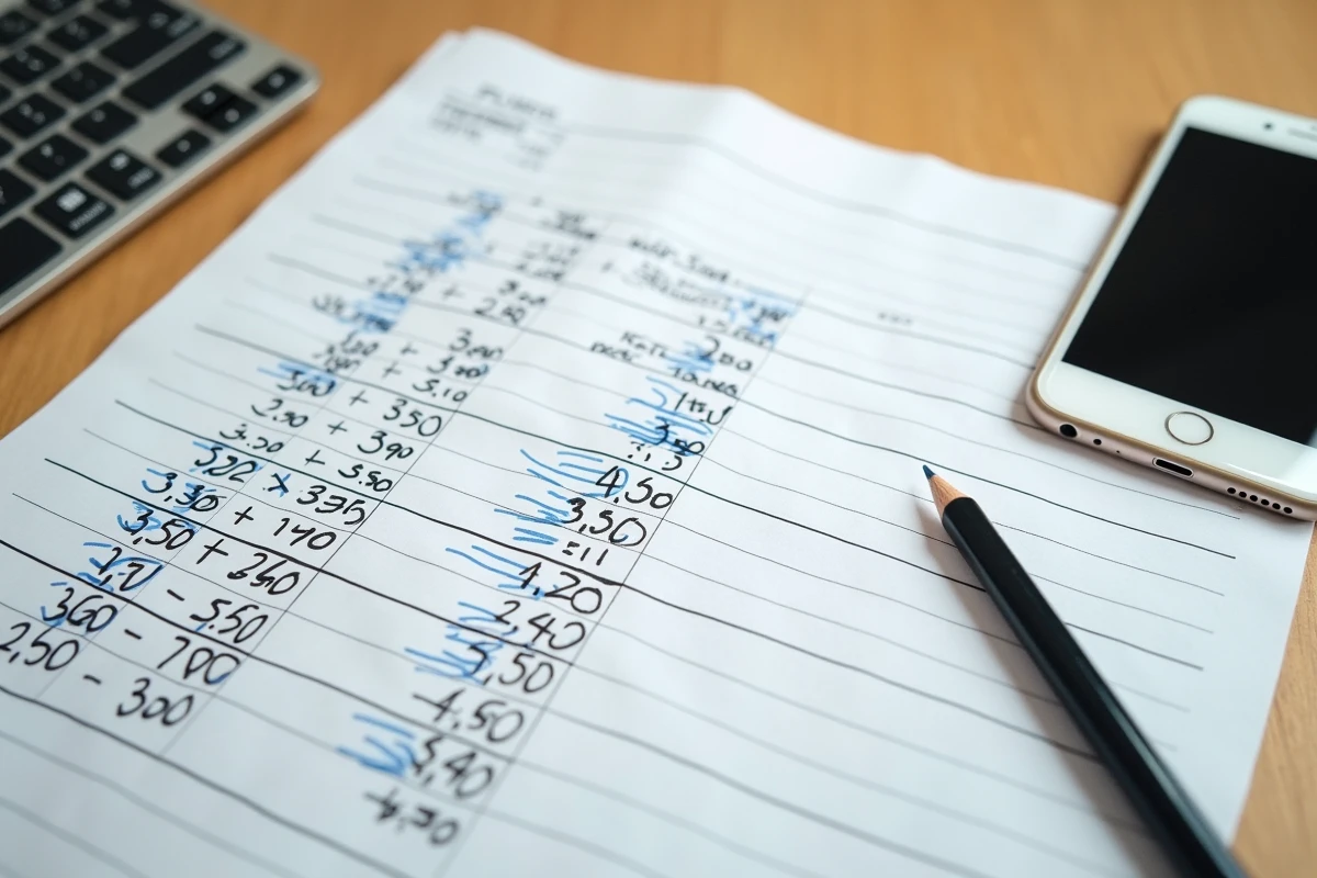 Vue de dessus d'une feuille Excel imprimée avec des conversions d'heures en centièmes annotées à la main sur un bureau en bois